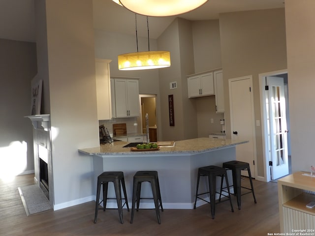 kitchen with hanging light fixtures, white cabinetry, a breakfast bar area, and high vaulted ceiling