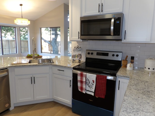 kitchen with white cabinets, sink, hanging light fixtures, light wood-type flooring, and appliances with stainless steel finishes