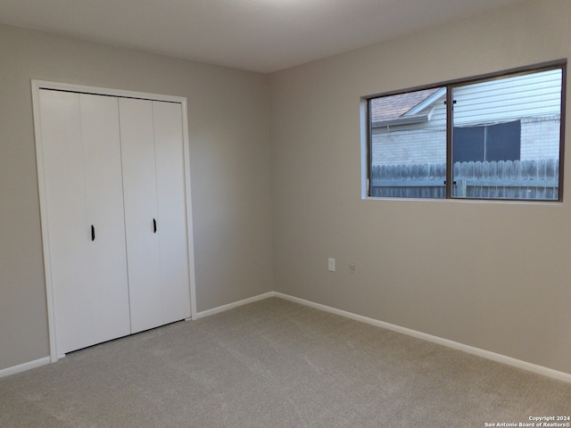 unfurnished bedroom with light carpet and a closet