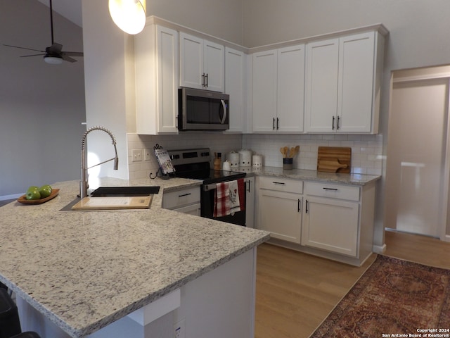 kitchen with white cabinets, stainless steel appliances, kitchen peninsula, and sink