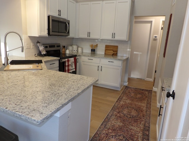 kitchen with backsplash, white cabinets, sink, light hardwood / wood-style floors, and stainless steel appliances