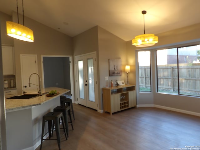 kitchen with pendant lighting, hardwood / wood-style floors, a breakfast bar area, and vaulted ceiling