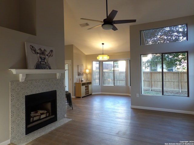 unfurnished living room with hardwood / wood-style floors, ceiling fan, and a high ceiling