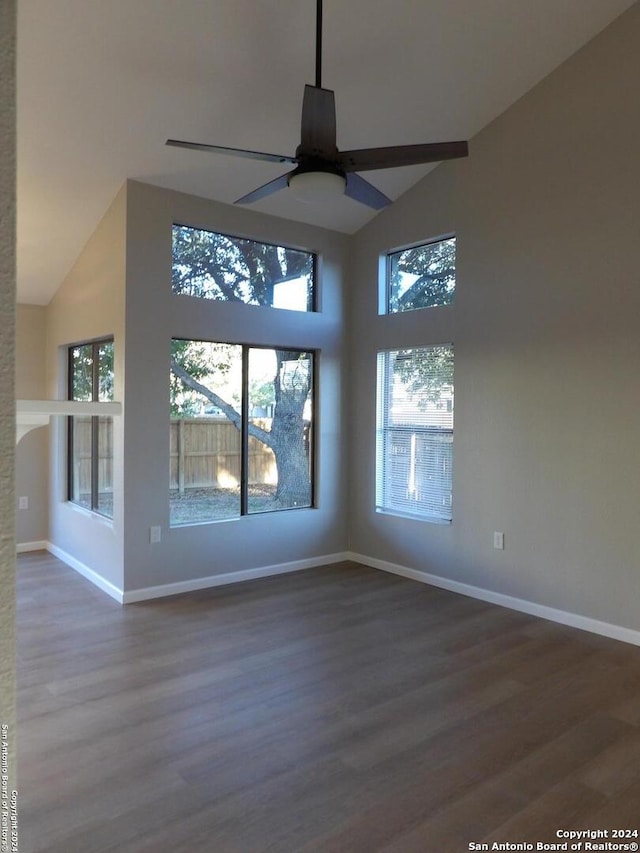 unfurnished room featuring ceiling fan, dark hardwood / wood-style flooring, high vaulted ceiling, and a healthy amount of sunlight