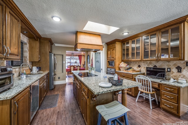 kitchen with a skylight, sink, a center island, dark wood-type flooring, and appliances with stainless steel finishes