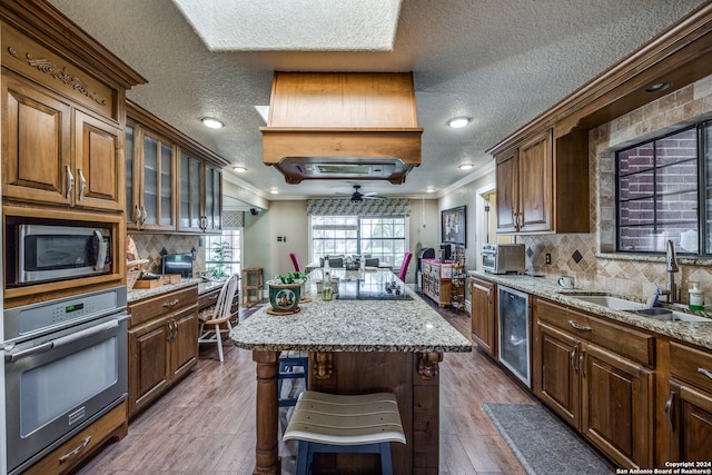 kitchen with hardwood / wood-style floors, a center island, sink, crown molding, and stainless steel appliances