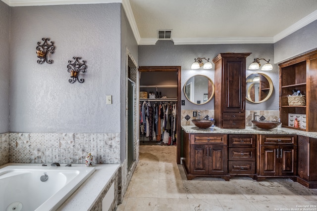 bathroom featuring tiled tub, vanity, a textured ceiling, and ornamental molding