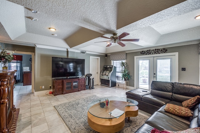 living room featuring ceiling fan, french doors, crown molding, a textured ceiling, and a tray ceiling