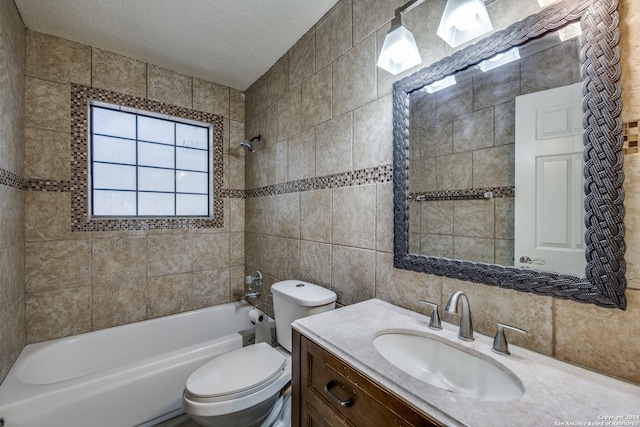 full bathroom featuring vanity, tiled shower / bath combo, toilet, a textured ceiling, and tile walls