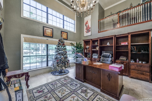 office space featuring ornamental molding, a towering ceiling, a healthy amount of sunlight, and a notable chandelier