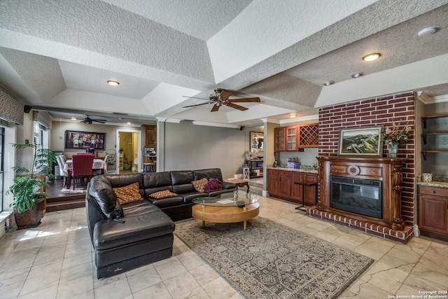 living room featuring a fireplace, ceiling fan, and a textured ceiling