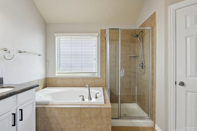 bathroom featuring plus walk in shower, vanity, and vaulted ceiling