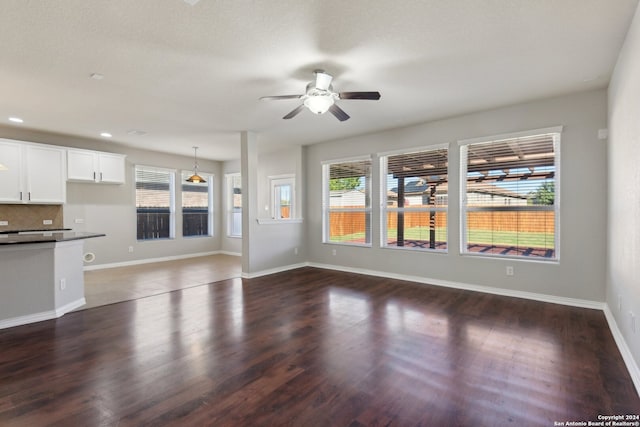 unfurnished living room with dark hardwood / wood-style floors and ceiling fan