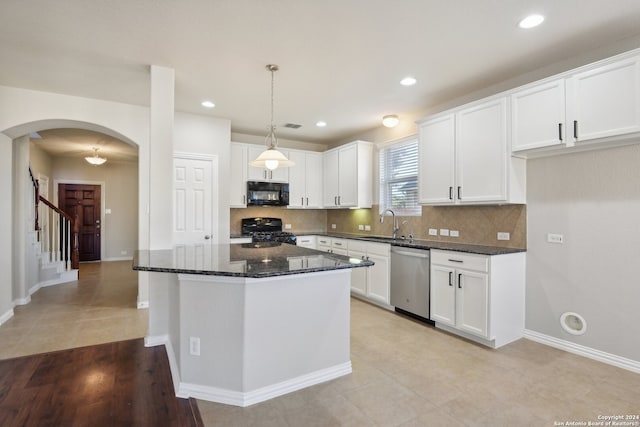 kitchen featuring decorative light fixtures, white cabinetry, dark stone countertops, and black appliances