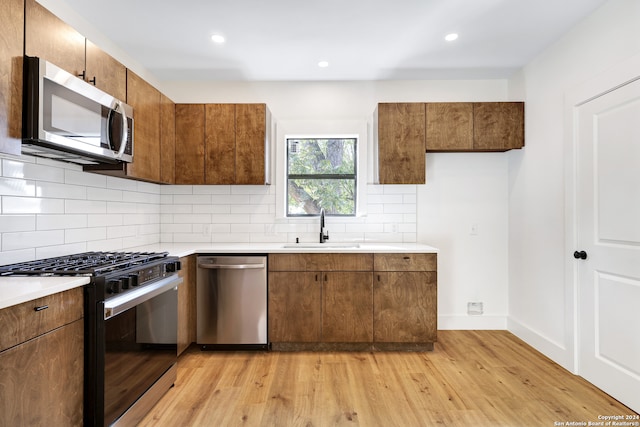 kitchen featuring decorative backsplash, light hardwood / wood-style floors, sink, and appliances with stainless steel finishes