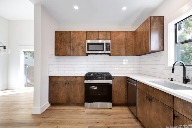 kitchen featuring tasteful backsplash, sink, stainless steel appliances, and light hardwood / wood-style flooring