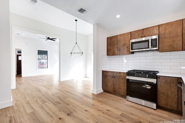 kitchen with ceiling fan, decorative backsplash, light wood-type flooring, decorative light fixtures, and stainless steel appliances