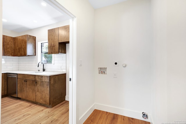 kitchen featuring backsplash, light hardwood / wood-style flooring, stainless steel dishwasher, and sink