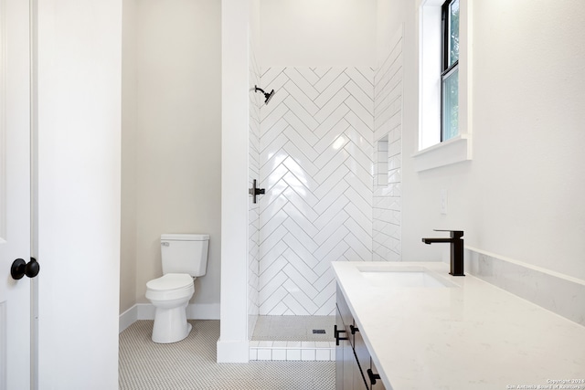 bathroom with tile patterned flooring, vanity, tiled shower, and toilet