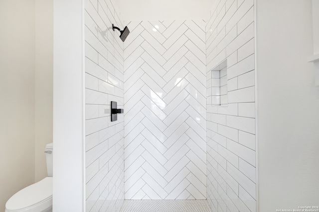 bathroom featuring tiled shower and toilet