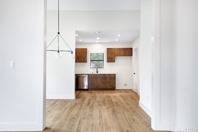 kitchen featuring sink, dishwasher, hanging light fixtures, backsplash, and light hardwood / wood-style floors