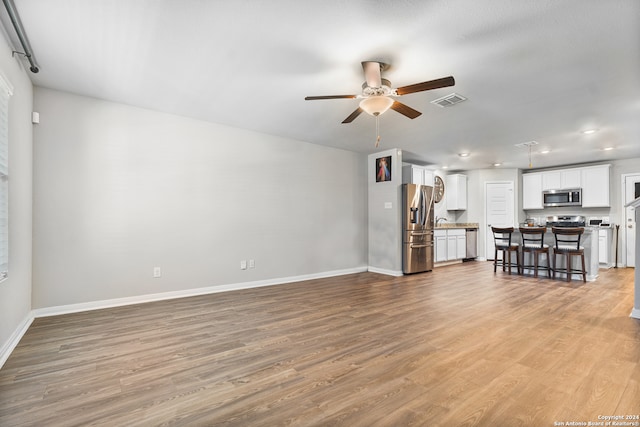 unfurnished living room featuring light hardwood / wood-style floors, ceiling fan, and sink