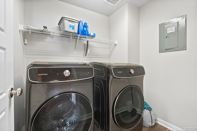 laundry room featuring electric panel, washer and dryer, and hardwood / wood-style flooring