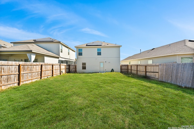 back of house with a lawn and solar panels