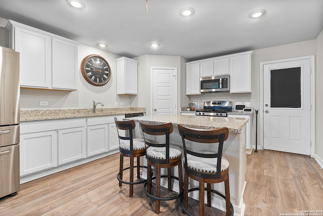 kitchen featuring appliances with stainless steel finishes, white cabinetry, and light stone counters