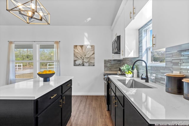 kitchen featuring decorative backsplash, appliances with stainless steel finishes, sink, white cabinets, and hanging light fixtures