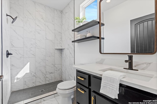 bathroom featuring a tile shower, vanity, and toilet