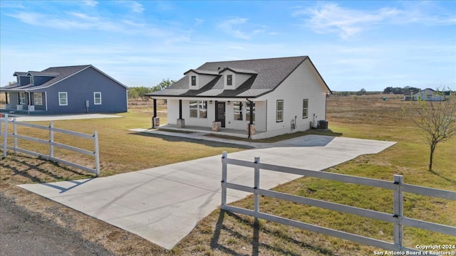 view of front of house featuring a porch, a front lawn, and central air condition unit