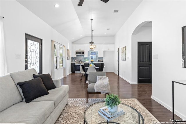 living room with ceiling fan with notable chandelier, vaulted ceiling, and dark wood-type flooring