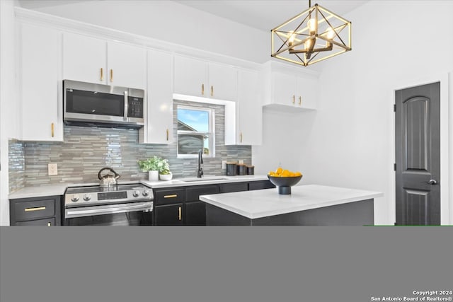 kitchen with sink, hanging light fixtures, tasteful backsplash, white cabinets, and appliances with stainless steel finishes