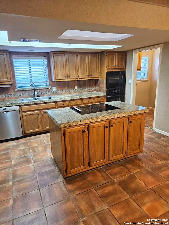 kitchen with a center island, black appliances, dark tile patterned flooring, a raised ceiling, and sink