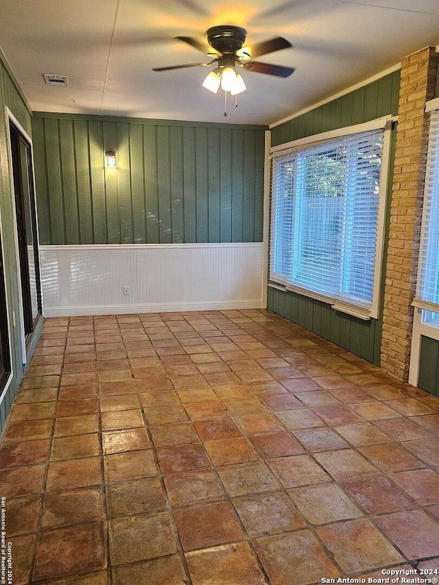 spare room featuring ceiling fan and wooden walls