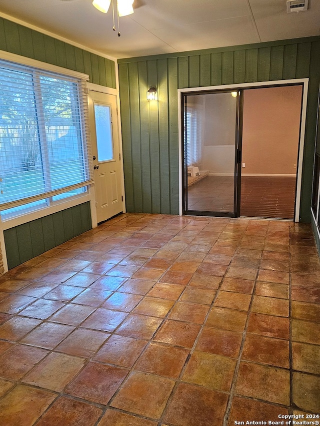 unfurnished room with ceiling fan and wooden walls