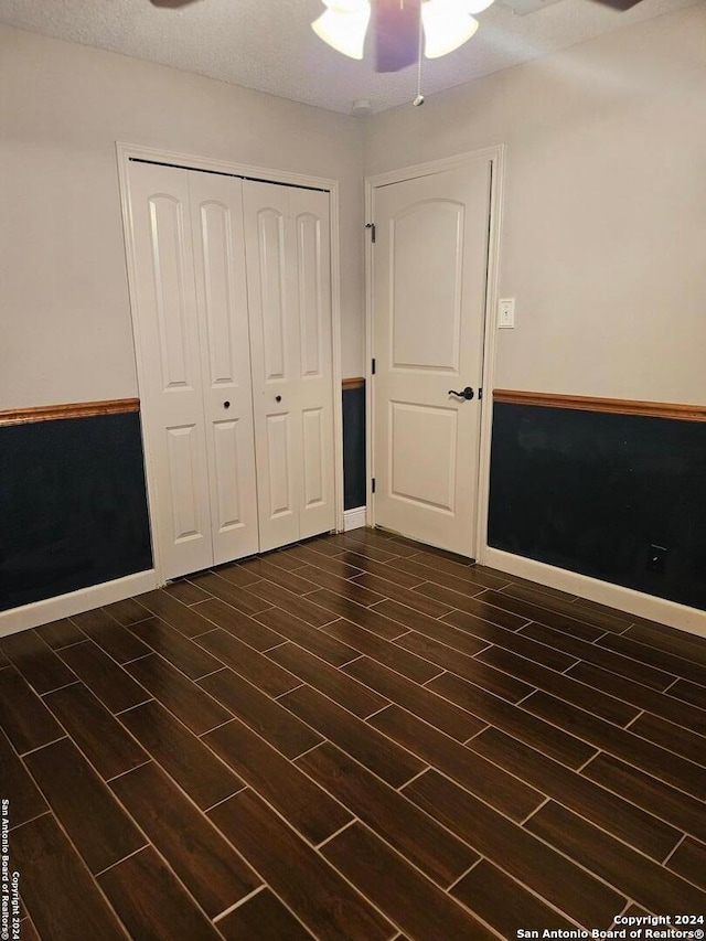 unfurnished bedroom featuring ceiling fan, dark hardwood / wood-style flooring, a textured ceiling, and a closet