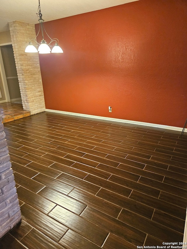 empty room featuring a chandelier and dark hardwood / wood-style flooring