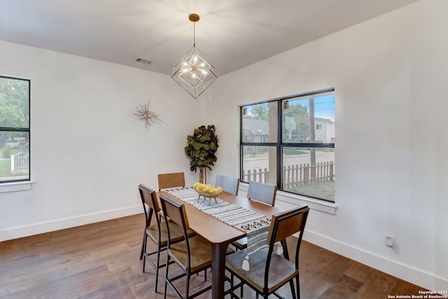 dining room with hardwood / wood-style flooring, vaulted ceiling, and a notable chandelier