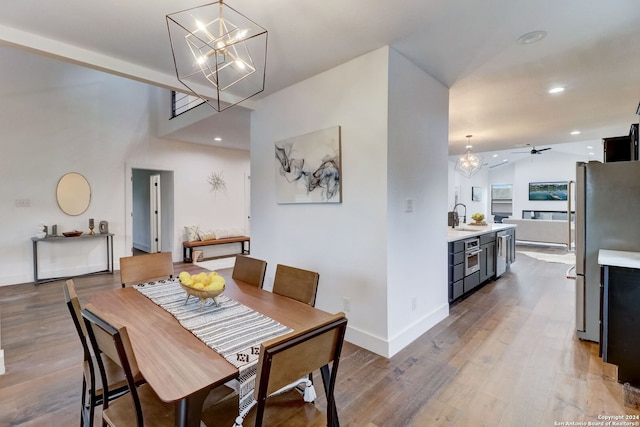 dining room with ceiling fan, sink, vaulted ceiling, and light wood-type flooring