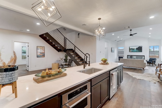 kitchen featuring pendant lighting, lofted ceiling, ceiling fan with notable chandelier, sink, and light hardwood / wood-style flooring