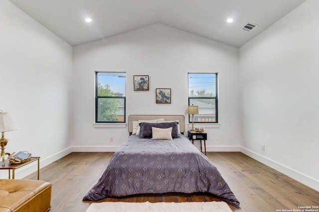 bedroom with light hardwood / wood-style floors, lofted ceiling, and multiple windows