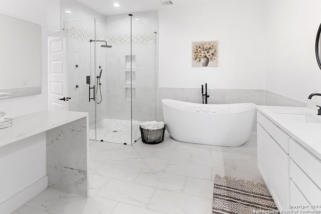 bathroom with vanity, separate shower and tub, and tile walls