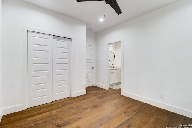 unfurnished bedroom featuring hardwood / wood-style floors, sink, ensuite bath, ceiling fan, and a closet