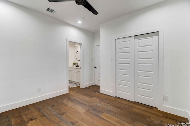 unfurnished bedroom with ensuite bath, ceiling fan, a closet, and dark hardwood / wood-style floors