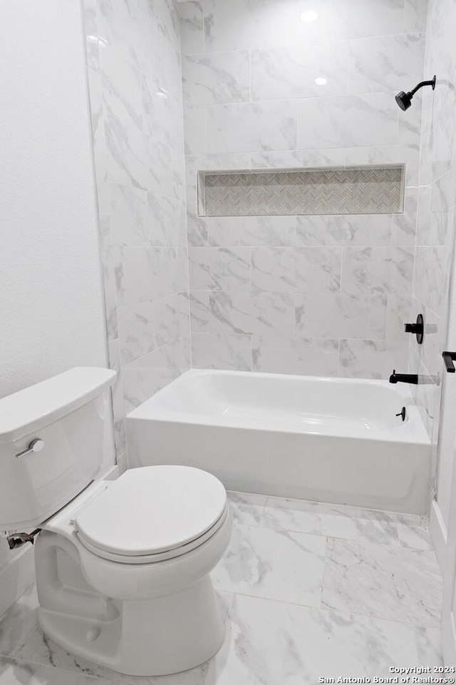 bathroom featuring tiled shower / bath combo and toilet