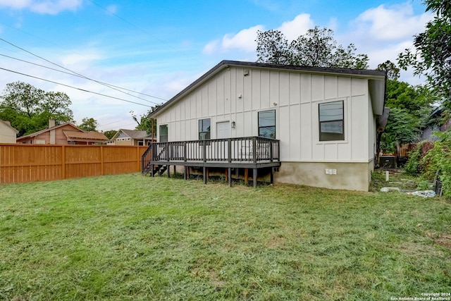 rear view of house featuring a wooden deck and a yard