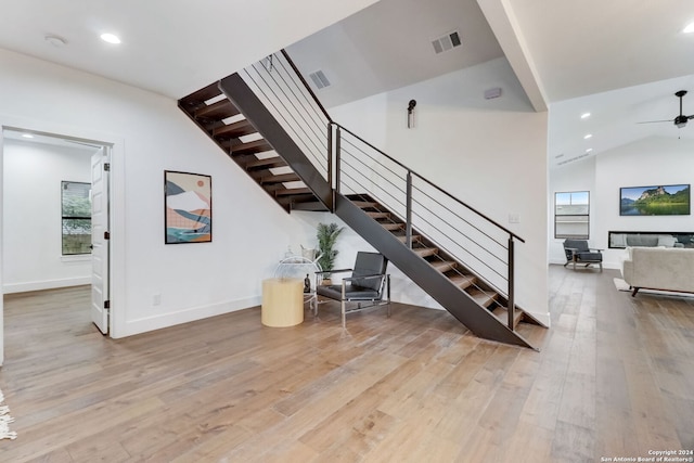 staircase with hardwood / wood-style floors, ceiling fan, and lofted ceiling