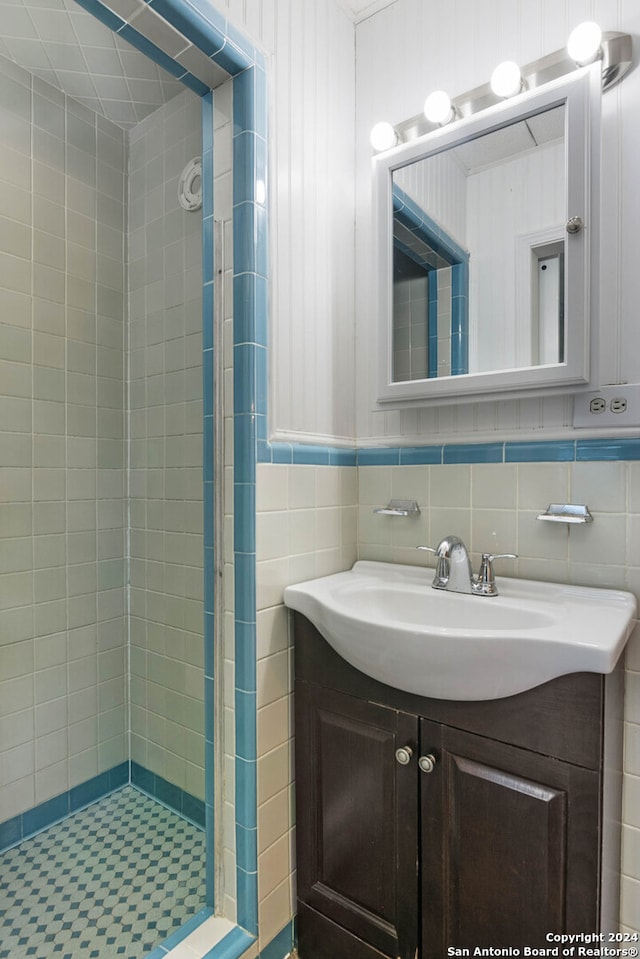 bathroom featuring a tile shower, vanity, and tile walls